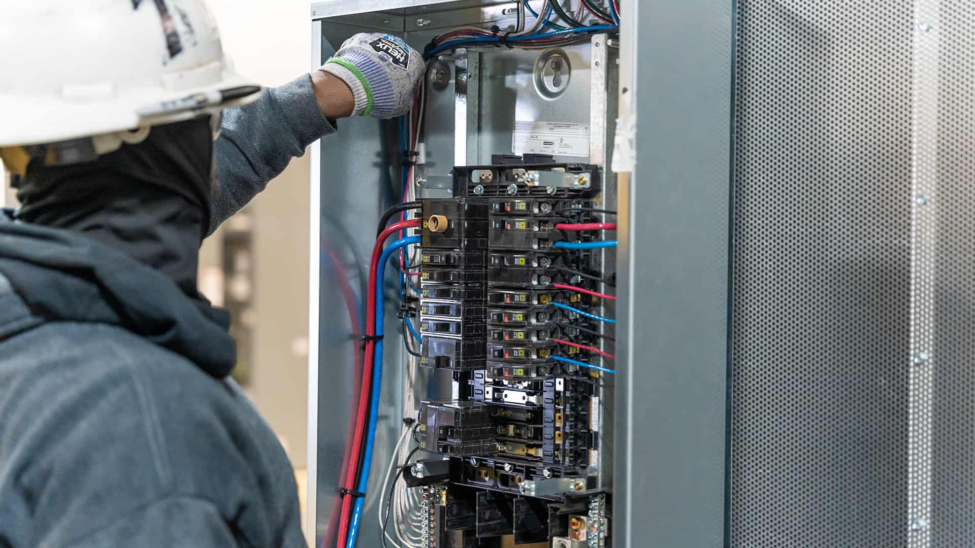 electrician working on wiring on fuse box Acoustical Sheetmetal Company