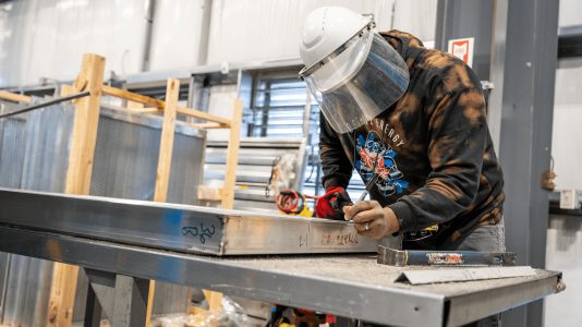 worker measuring for enclosure assembly Acoustical Sheetmetal Company