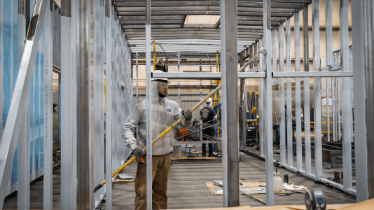 worker painting metal frame of enclosure Acoustical Sheetmetal Company