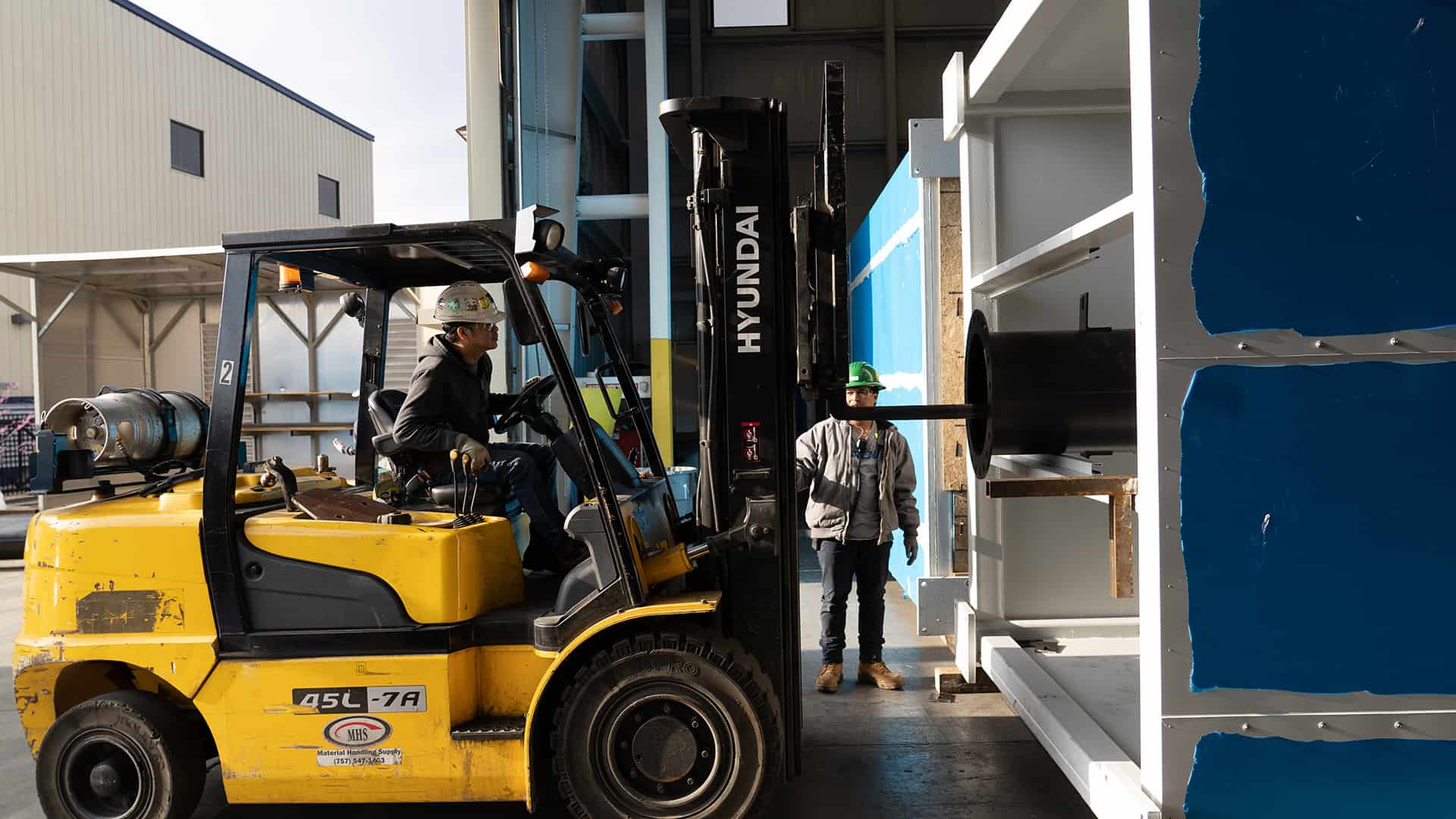 worker on forklift placing exhaust pipe in plenum Acoustical Sheetmetal Company