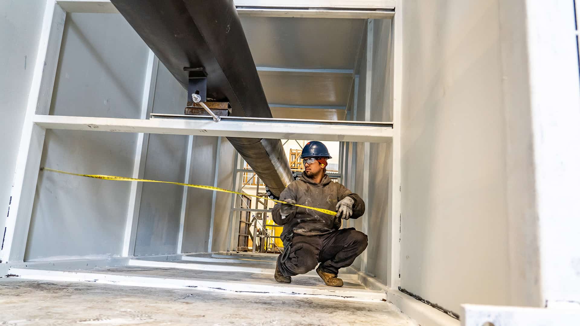 worker measuring plenum Acoustical Sheetmetal Company